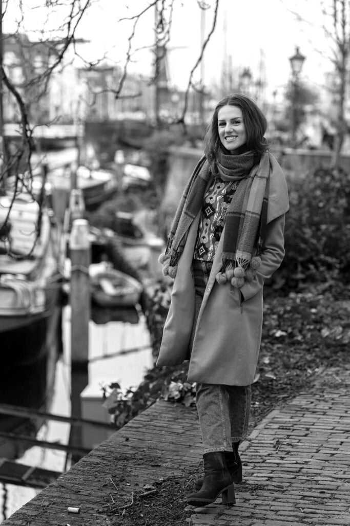 Black and white full-body city portrait of a smiling woman.